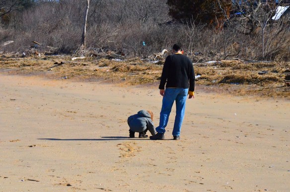 Martin shows Adrian how he can write letters in the sand.