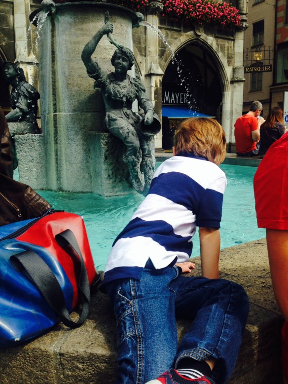 Martin has been feeling better since we arrived in Munich. In this photo, he is checking out a fountain in Marianplatz, in the city center. He just tossed in some Euro coins.